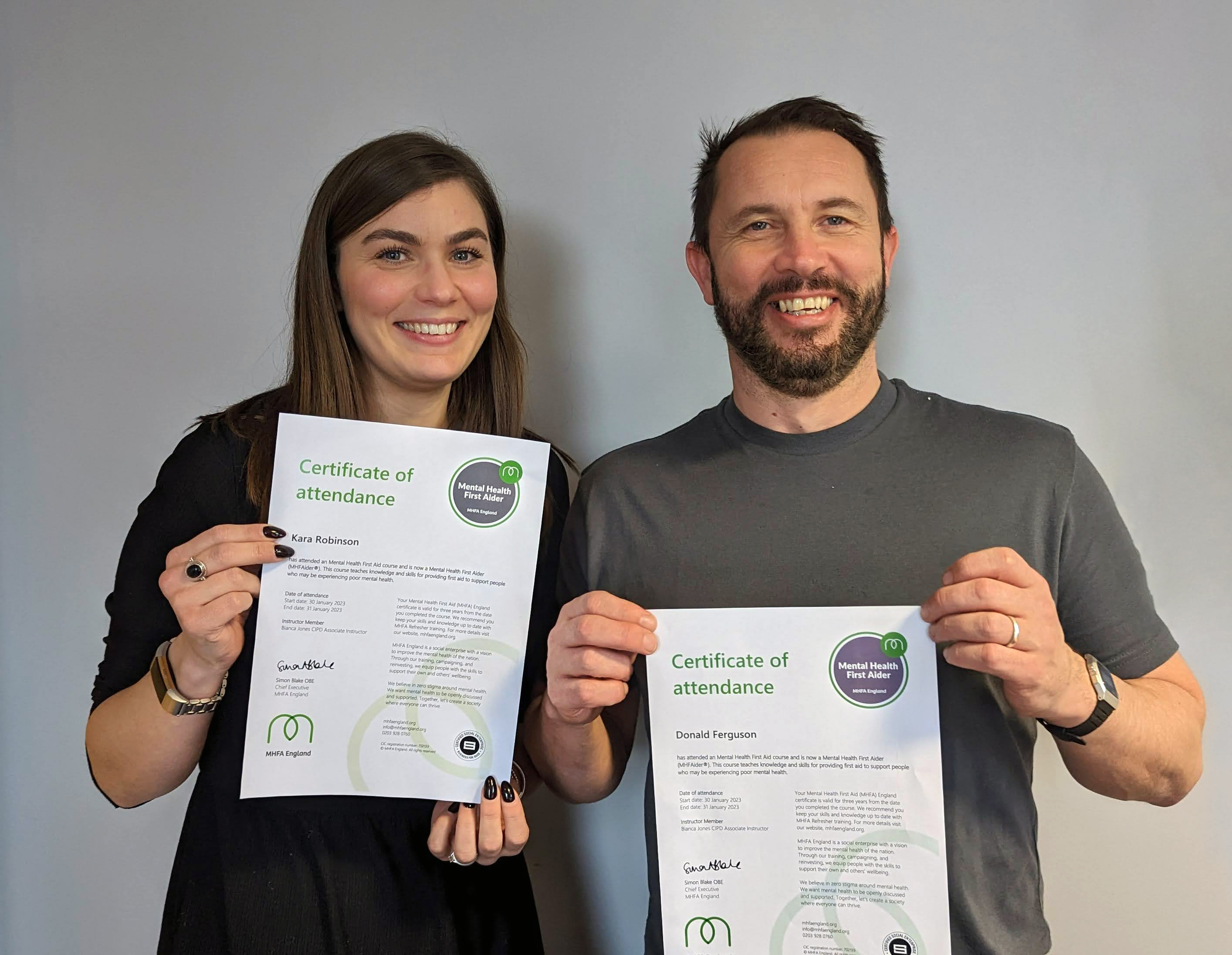 An image of Greenbelt staff Donald and Kara posing with their certificates following mental health awareness training