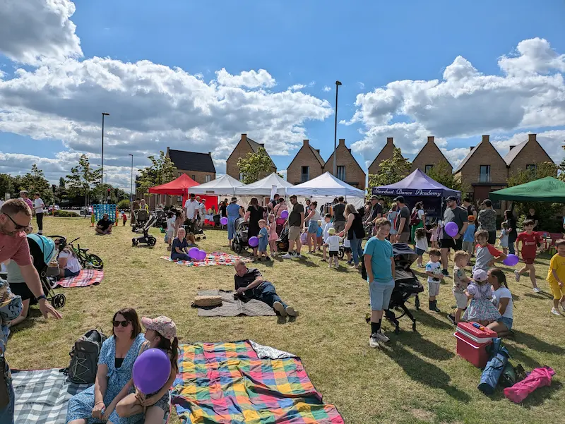 People gathered at an outdoor community fete with colourful bunting.